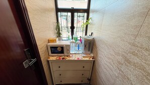 A small kitchenette with a microwave, a water bottle, a coffee maker, and a potted plant. - Sleep Inn (Kowloon)