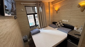 A compact hotel room with a bed, a small desk, a wall-mounted TV, and a window with curtains. - Sleep Inn (Kowloon)