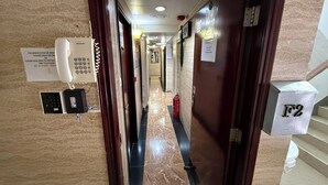 A hotel hallway with a telephone, a fire extinguisher, and a sign indicating room number F2. - Sleep Inn (Kowloon)