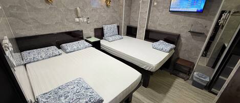 A hotel room with two beds, a clock, a TV, and a shower.