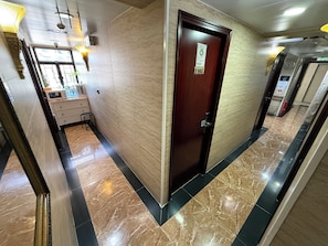 Un couloir avec une porte en bois, un comptoir d’accueil et un sol en marbre.