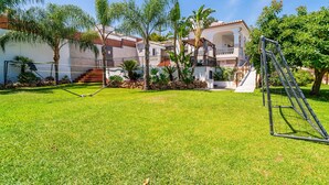 A well-maintained outdoor area with a volleyball net, palm trees, and a building with a balcony. - Cubo's Villa Esmeralda / private pool / garden / air conditioning / fireplace / free Wi-Fi (Alhaurín el Grande)