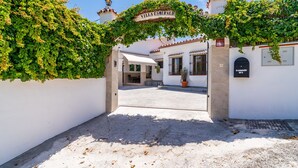 A villa entrance with a sign, a covered area, and a potted plant. - Cubo's Villa Esmeralda / private pool / garden / air conditioning / fireplace / free Wi-Fi (Alhaurín el Grande)