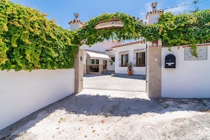 L’entrée d’une villa, avec une enseigne, un espace abrité et un pot de fleurs.