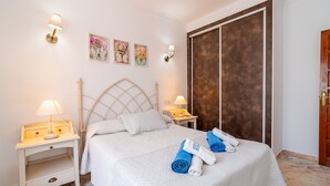 A neatly made bed with rolled towels, a headboard, bedside tables with lamps, and artwork on the wall. - Cubo's Villa Esmeralda / private pool / garden / air conditioning / fireplace / free Wi-Fi (Alhaurín el Grande)