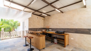 A modern kitchen with a wooden island, bar stools, and a tiled floor. - Cubo's Villa Esmeralda / private pool / garden / air conditioning / fireplace / free Wi-Fi (Alhaurín el Grande)