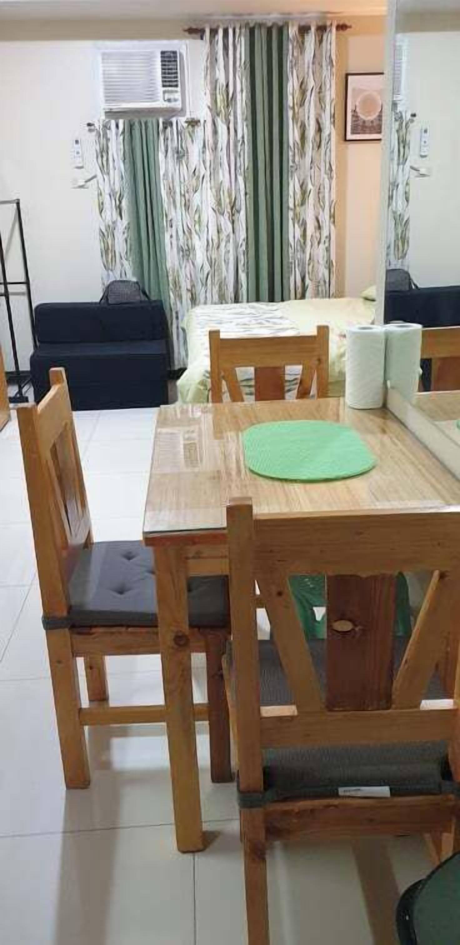 A dining area with a wooden table and chairs, a green placemat, and a sofa in the background.