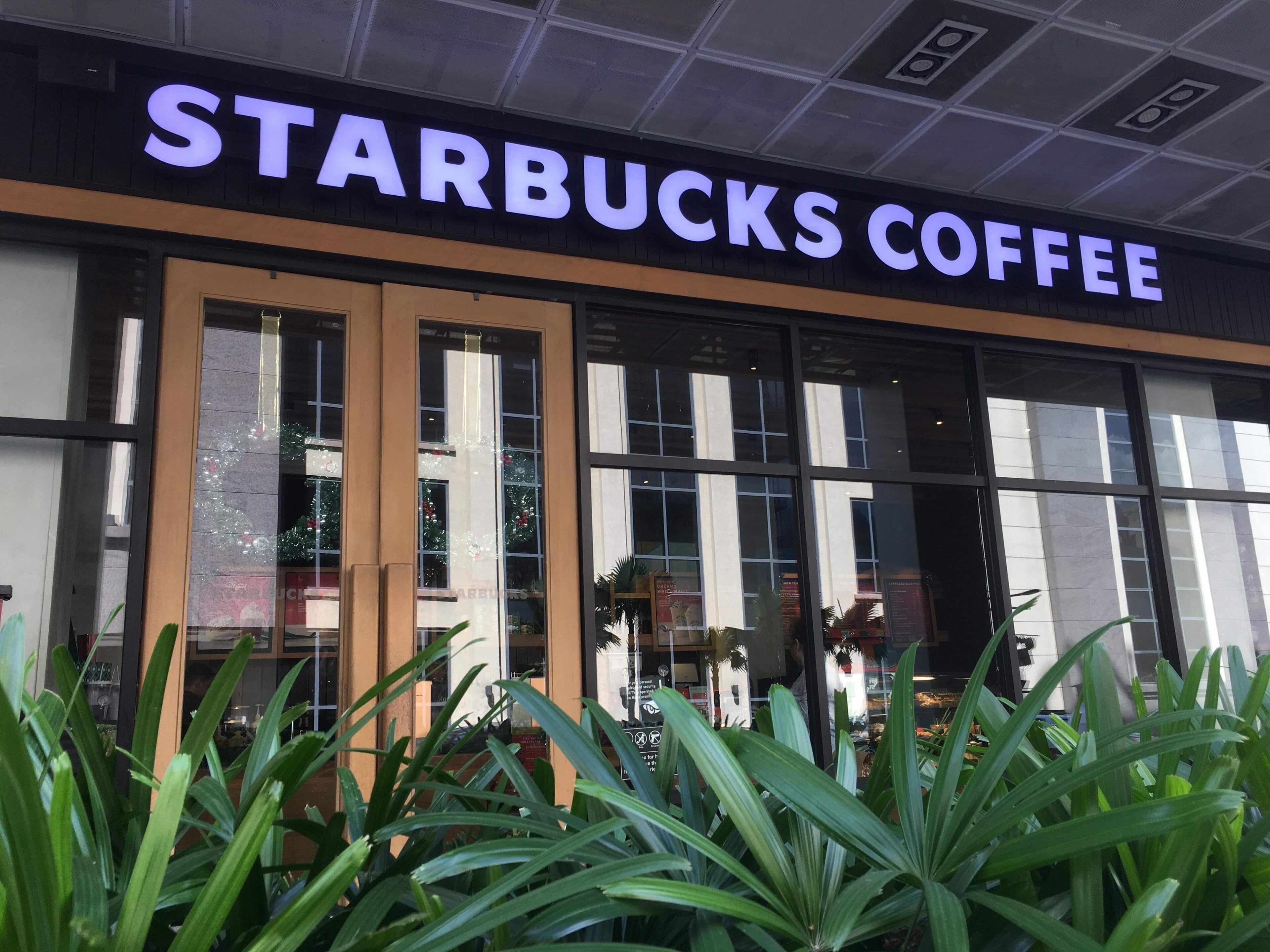 The exterior of a Starbucks Coffee store with large glass windows and a sign above the entrance.