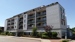 Een hotel met meerdere verdiepingen, balkons, een parkeerbord en een heldere lucht.