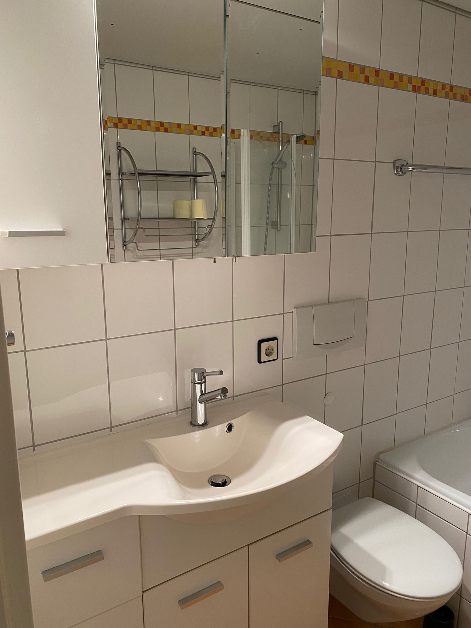 A bathroom with a white sink, mirror, and toilet.