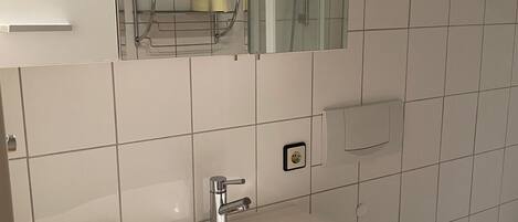 A bathroom with a white sink, mirror, and toilet.