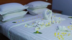 A neatly made bed with white linens, pillows, and a towel arranged in a swan shape. - Bagan Hmwe Hotel (Nyaung-U)