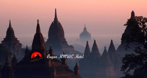 A view of temple structures at sunset with the Bagan NMWE Hotel logo.