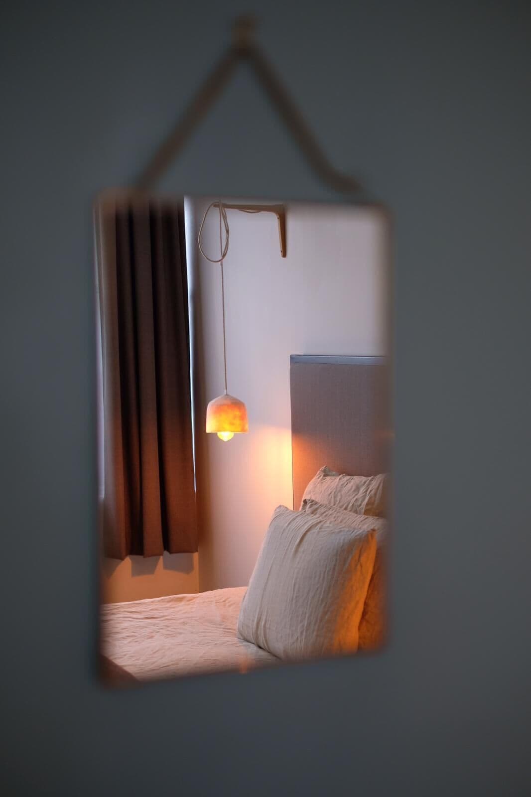 A bedroom with a bed, curtains, a hanging lamp, and a wall-mounted light fixture.