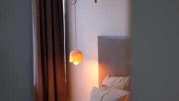 A bedroom with a bed, curtains, a hanging lamp, and a wall-mounted light fixture.