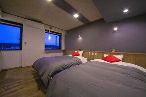 A hotel room with two beds, a window with a view, and a ceiling with recessed lighting.