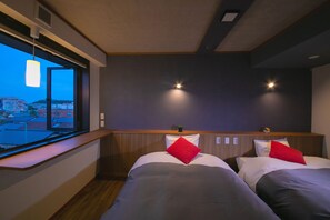 A hotel room with two beds, a window with a view of buildings, and a wooden headboard. - Narita AIC Airport Hotel (Narita)