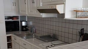 A kitchen with white cabinets, a microwave, a coffee maker, and a tiled backsplash.