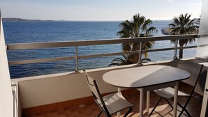 A balcony with a table and chairs overlooking the sea.