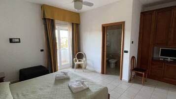 A hotel room with a bed, a chair, a television, and a bathroom visible through an open door.