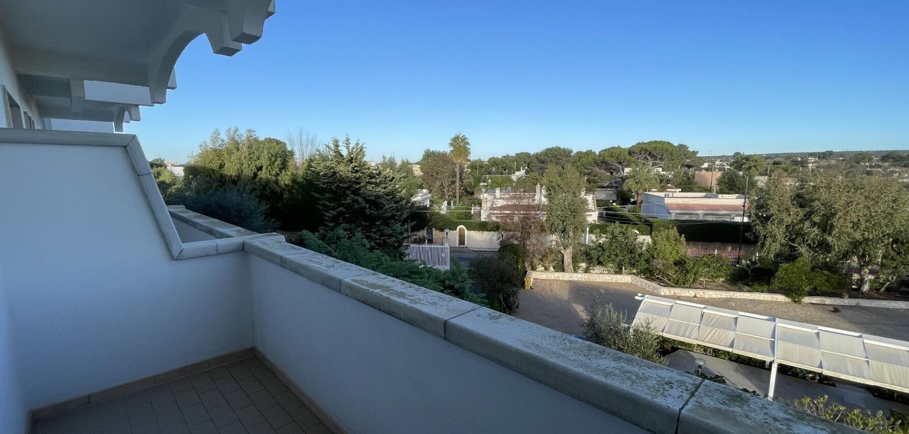 A balcony with a clear view of a residential area, including houses and trees.
