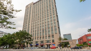 Un edificio alto y moderno con varios pisos y una entrada destacada.