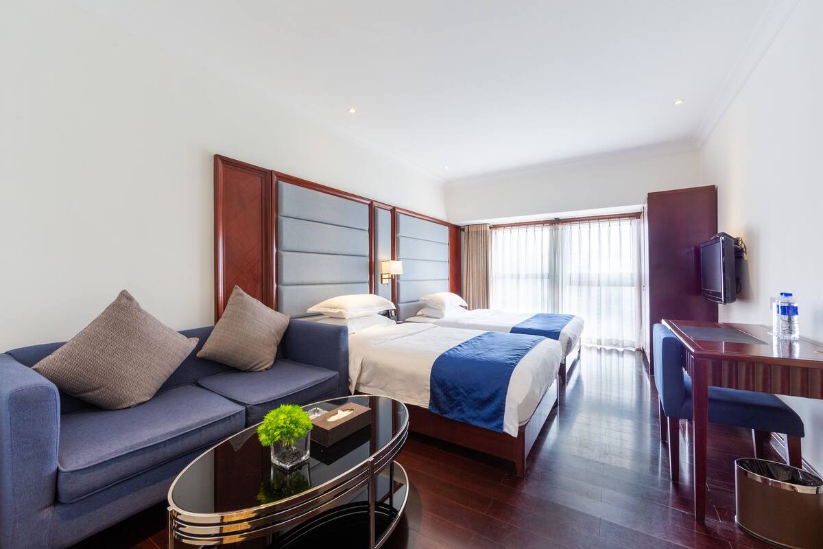 Ein Hotelzimmer mit Bett, Sofa, Schreibtisch und Fernseher.