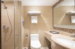 A bathroom with a glass-enclosed shower, a toilet, a sink, and a mirror.