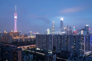 A high-rise urban skyline with illuminated buildings, including a prominent tower with a spire.