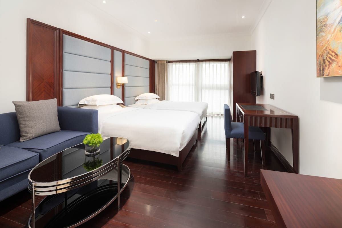Ein Hotelzimmer mit einem großen Bett, einer Couch, einem Schreibtisch und einem Fernseher.