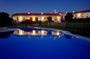 A large swimming pool with a house in the background.