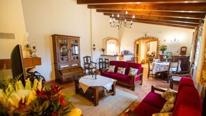 A cozy living room with a red sofa, wooden furniture, and a chandelier.