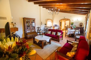 Una sala de estar acogedora con un sofá rojo, muebles de madera y una araña.