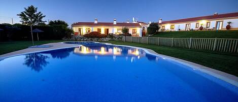 A large swimming pool with a house in the background.