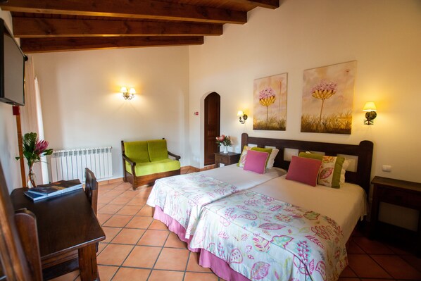 A bedroom with a bed, two bedside tables, a chair, a desk, and a radiator. - Turismo Rural Monte João Roupeiro (Aljezur)