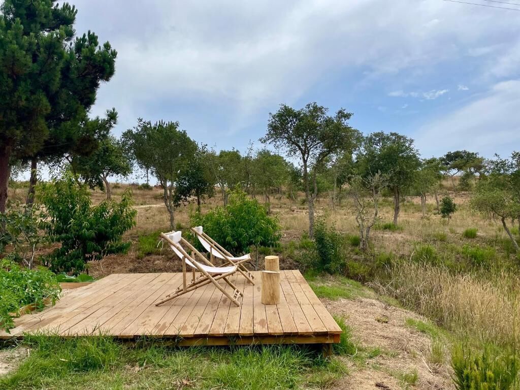 Une terrasse en bois avec deux chaises longues et un poteau en bois.