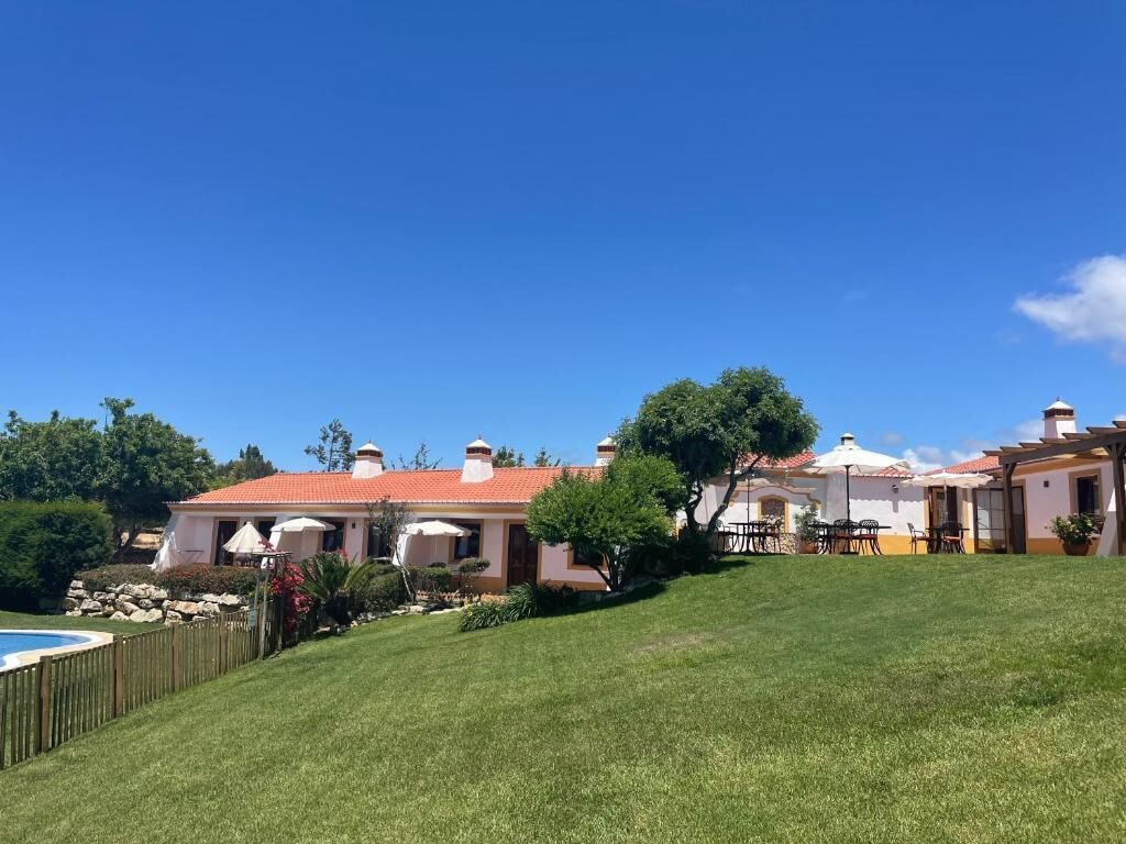 Una propiedad residencial con piscina, césped cuidado y zona de patio con mobiliario exterior.