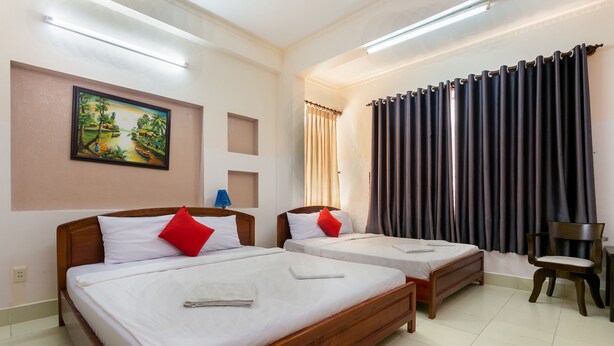 A hotel room with two wooden beds, a painting on the wall, a window with curtains, and a chair. - Star Hotel (Ho Chi Minh City)