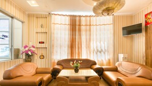 A modern living room with a sofa set, a coffee table, and a TV mounted on the wall. - Star Hotel (Ho Chi Minh City)