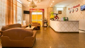 A hotel reception area with a curved reception desk, a television mounted on the wall, and a large window with curtains. - Star Hotel (Ho Chi Minh City)