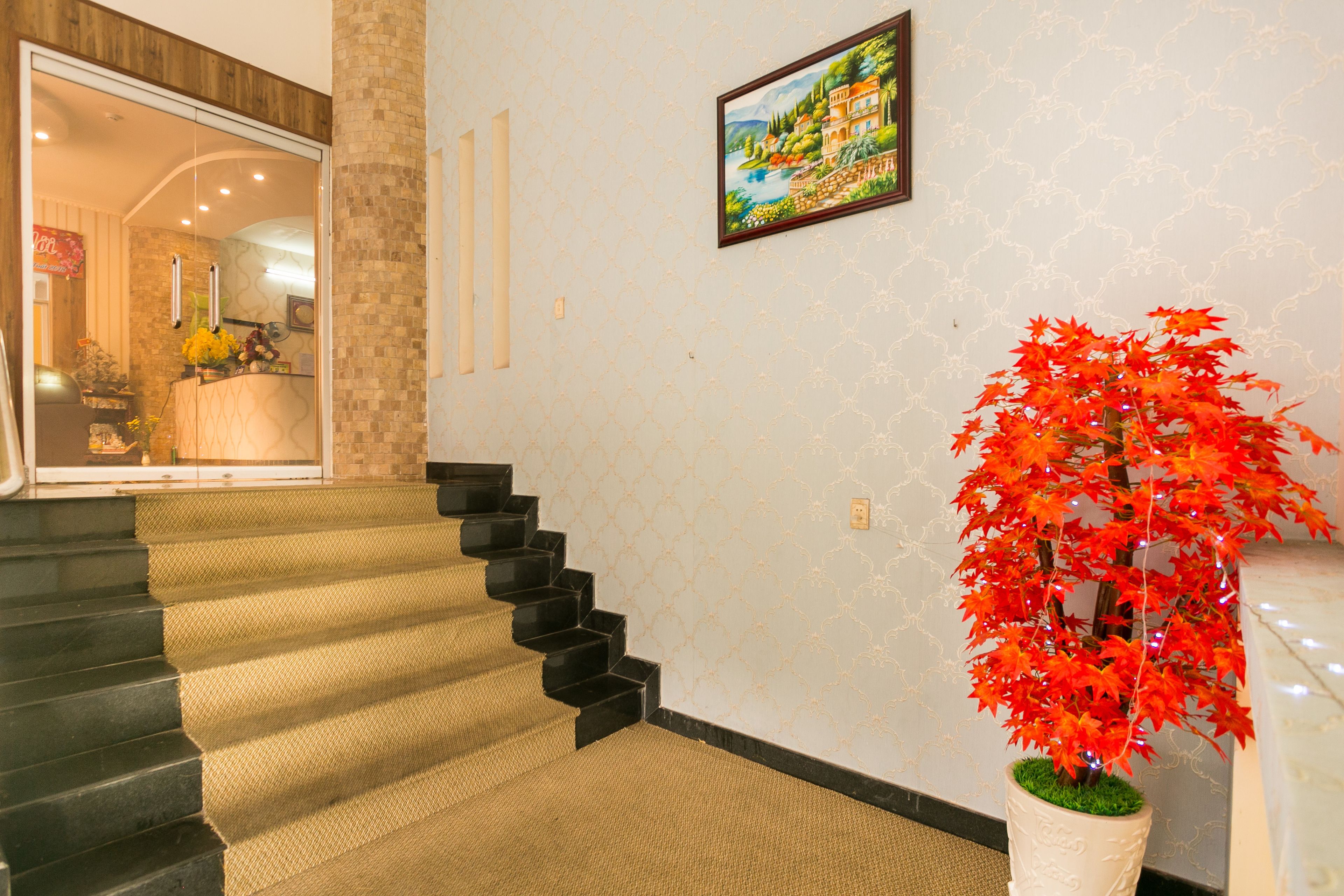A staircase with a patterned carpet leading to a room with a large window and a framed painting on the wall.