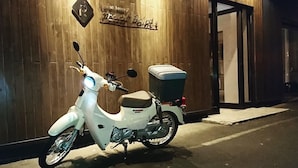 Un scooter blanc est garé devant un mur en bois sur lequel est affiché un panneau indiquant « Brook Point ».
