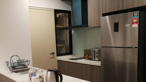 Eine moderne Küche mit einem Edelstahl-Kühlschrank, einem eingebauten Ofen und einer weißen Arbeitsplatte.