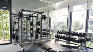 Ein Fitnessstudio mit Krafttrainingsgeräten, Bänken und Kurzhanteln.