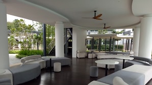 Ein moderner Außenloungebereich mit Sofas, runden Tischen und Deckenventilatoren.