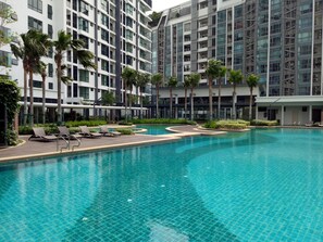 A modern hotel with a large swimming pool, palm trees, and a multi-story building with balconies. - Sunway Velocity with KLCC View - AJ Home (Kuala Lumpur)
