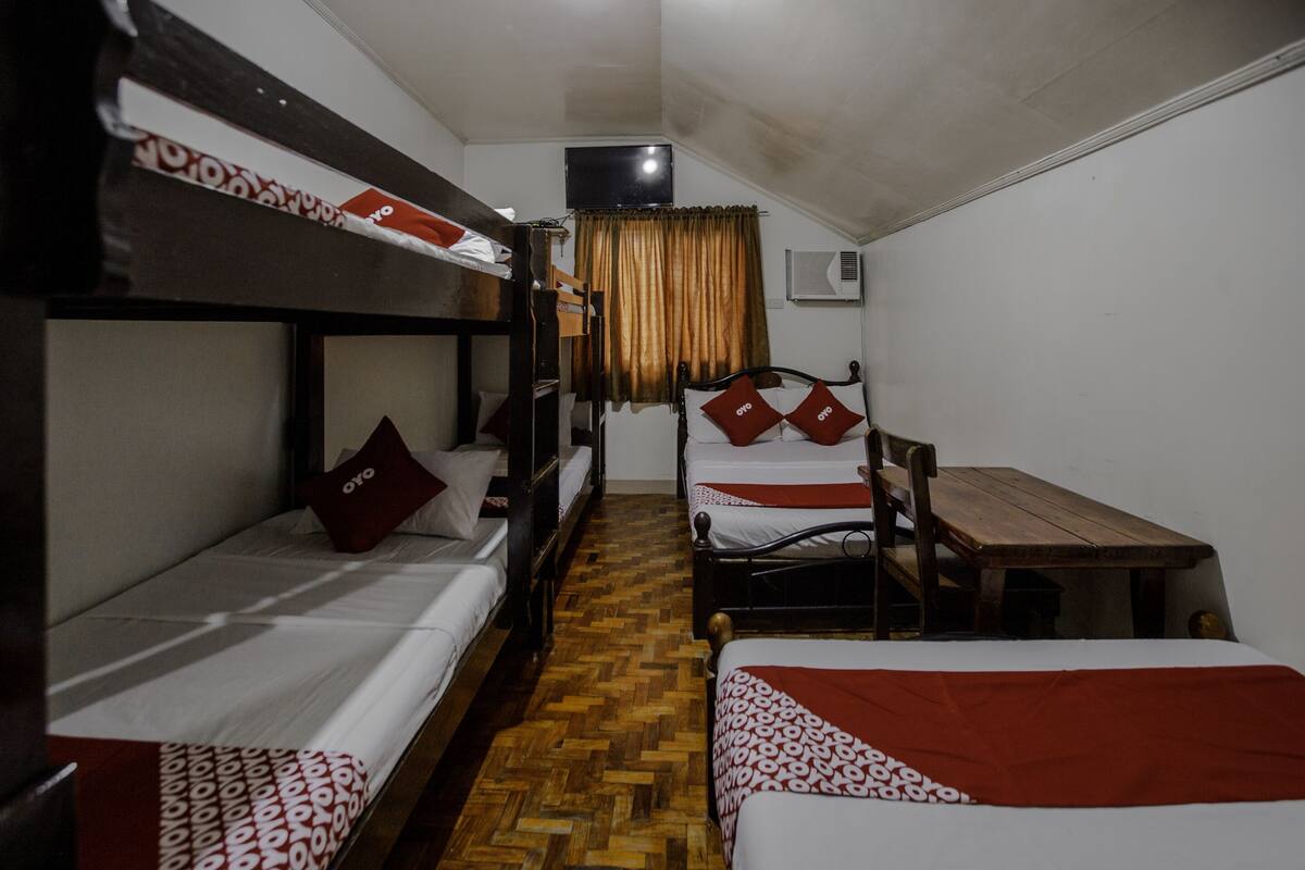 Un dormitorio con literas, una mesa de madera y un televisor instalado en la pared.
