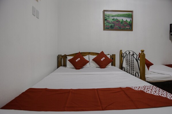 A bed with a wooden headboard, two red pillows, and a white bedspread.