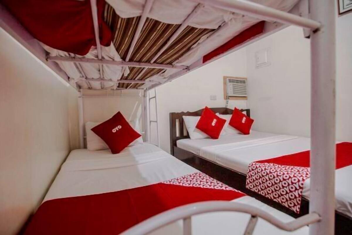 Un dormitorio con literas, almohadas rojas y una colcha estampada.