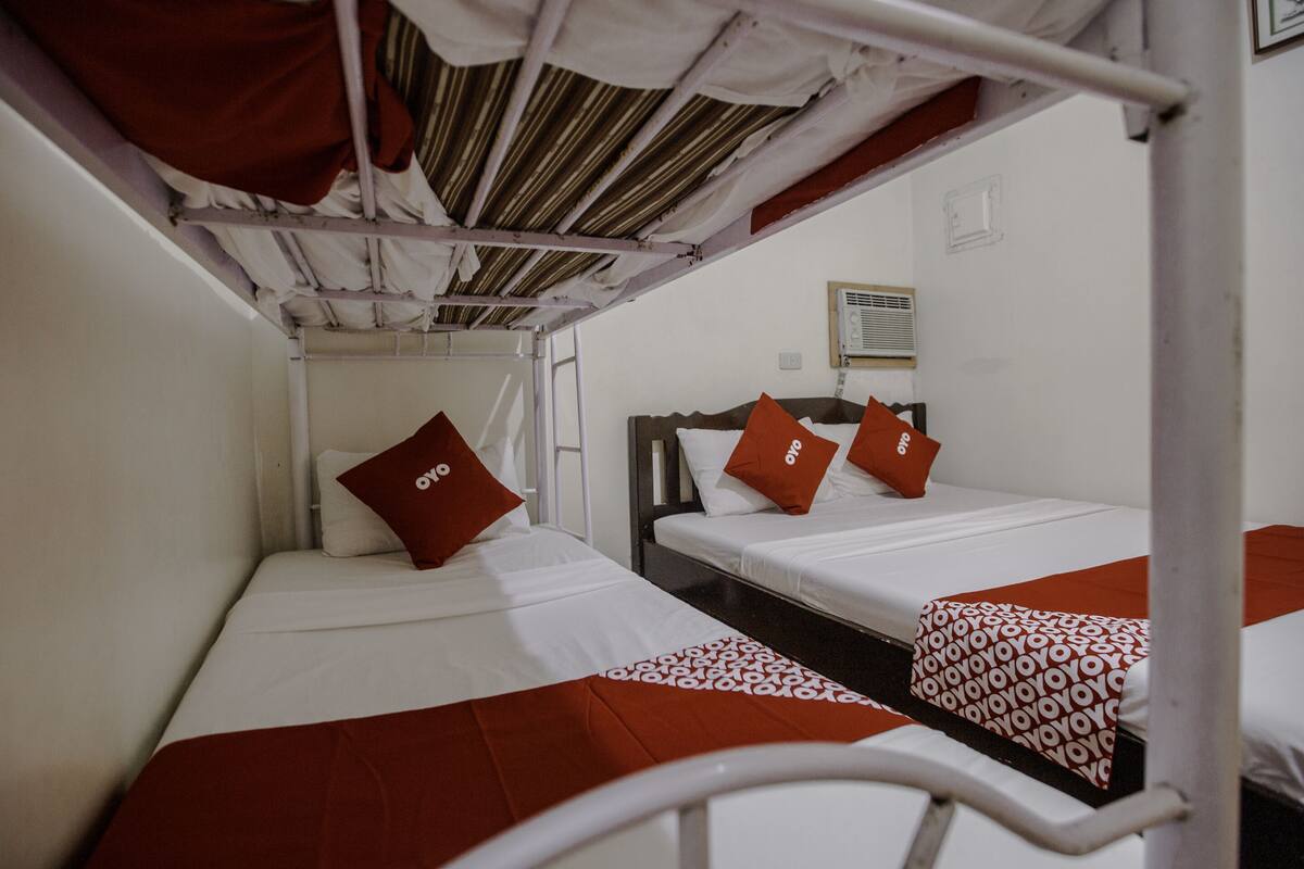 Un dormitorio con literas, cada una con una almohada roja y una manta estampada.